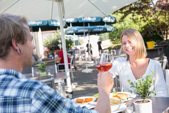 Zwei Personen stoßen mit Wein im Jägerhaus Biergarten an.